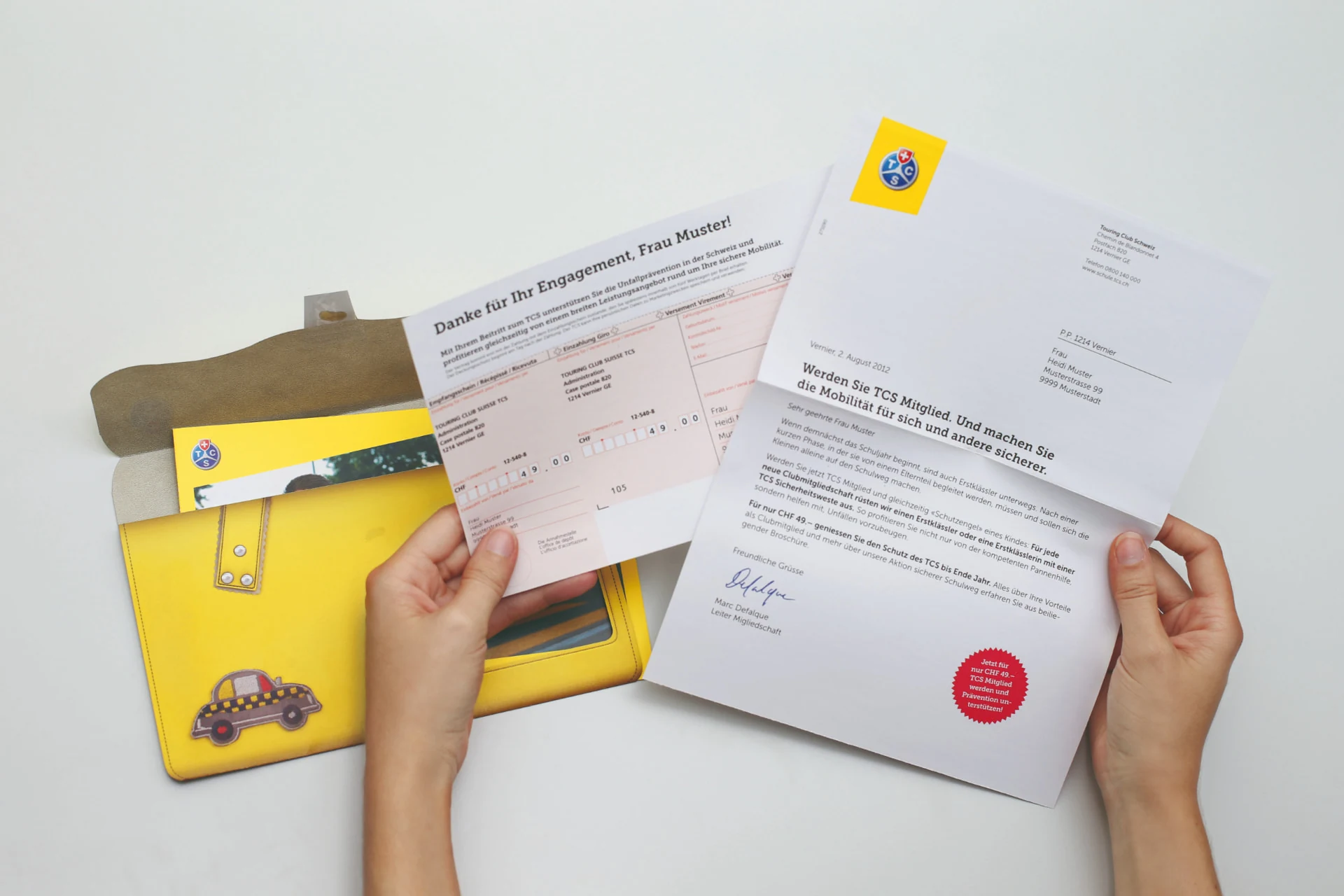 Geöffnete gelbe TCS Schultaschen-Hülle mit personalisiertem Anschreiben und weiteren Mailingelementen.