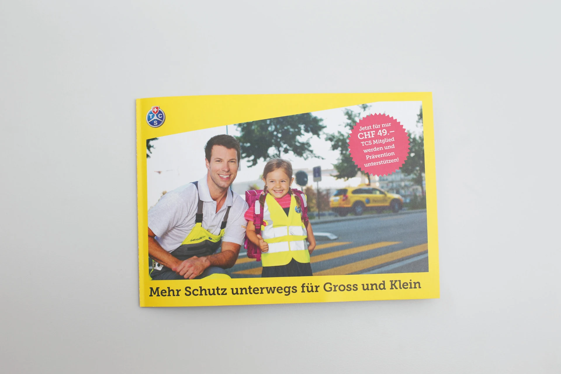 Geschlossene gelbe TCS Broschüre mit dem Titel Mehr Schutz unterwegs für Gross und Klein.